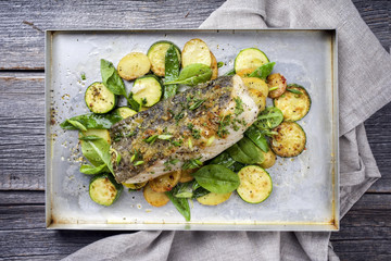 Fried cod fish fillet with vegetable and potatoes as top-view on a tray