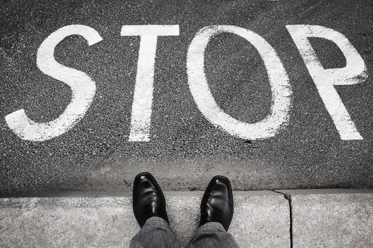 Feet of a man and stop road marking label