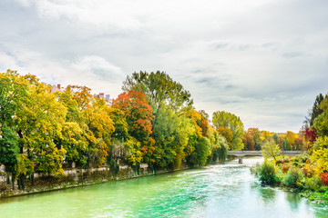 View on Isar river an colorful trees in autumn landscape in Munich