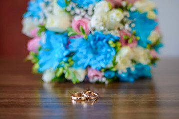 Engagement rings and wedding bouquet on a wooden table