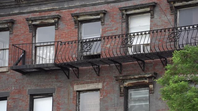 Exterior day establishing shot of a Brooklyn style apartment building in New York City. Windows sit over the fire escape on a brick facade