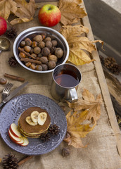 A composition of nuts, pancakes, bananas and apple on a nice autumn themed background