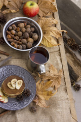 A composition of nuts, pancakes, bananas and apple on a nice autumn themed background
