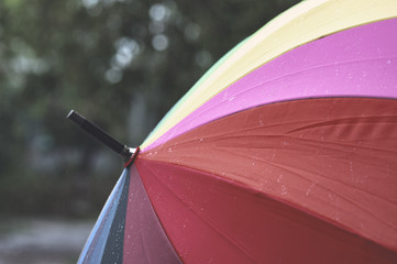 Rain drops falling on rainbow umbella . Concept cold autumn. rainy weather.
