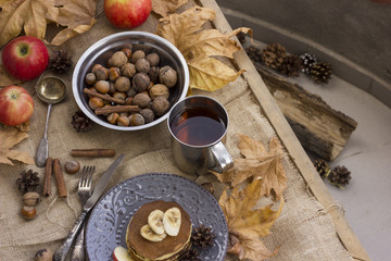A composition of nuts, pancakes, bananas and apple on a nice autumn themed background