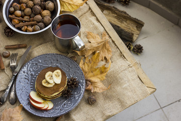 A composition of nuts, pancakes, bananas and apple on a nice autumn themed background