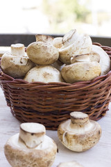 fresh mushrooms in a basket on the wooden table.