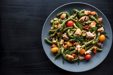 Salmon and spinach spaghetti served on wooden background with blank space .