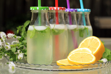 Homemade lemonade in glass bottles on a glass table