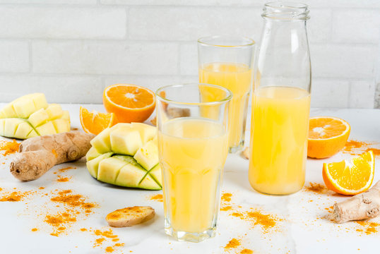 Indian cuisine recipes. Healthy food, detox water. Traditional Indian mango, orange, turmeric and ginger smoothie, on a white marble table. Copy space