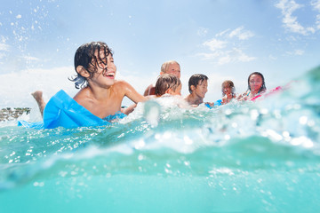 Group of happy kids play in the sea on matrass