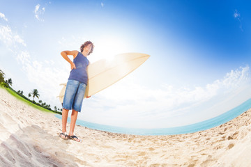 Fototapeta na wymiar Confident teenager on beach with surfboard