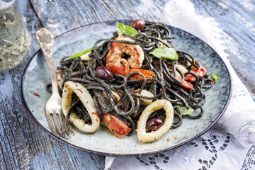Italian linguine con tinta de calamari and prawns with olives as close-up on a plate