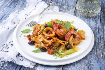 Italian tagliatelle con gamberi e calamari in salsa di pomodoro with olives and peperoni as close-up on a plate