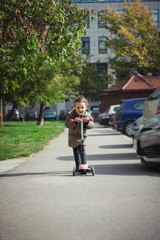 Cute little girl riding push scooter.