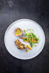 Fried pork tenderloin with vegetable and passion fruit as top view on a plate
