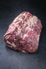 Fototapeta premium Raw dry aged Kobe rib eye steak as close-up on a black board