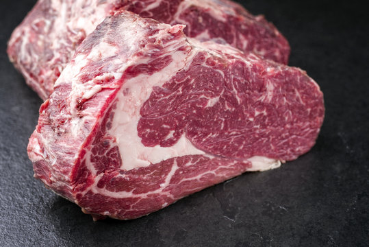 Two Raw dry aged Kobe rib eye Steak as close-up on a black board