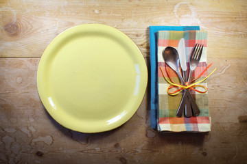Bright and colorful casual rustic place setting on a vintage wood table
