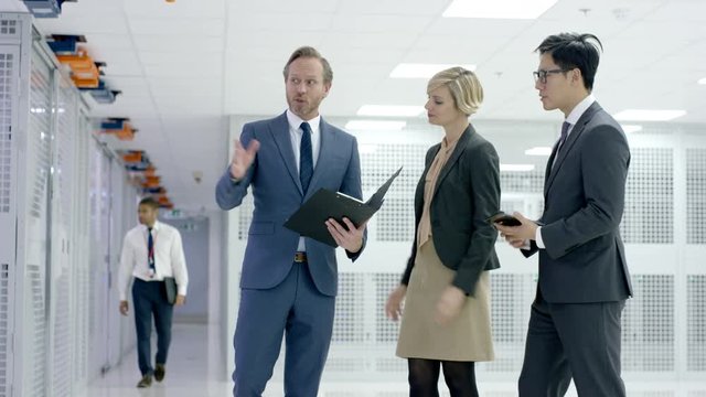 Business team in a meeting in data center and technician checking the system with laptop.