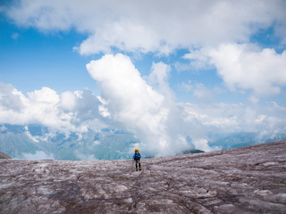 Climber standing on dirty glacier with clouds floating around him
