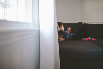 Little girl looking at a device wearing headphones
