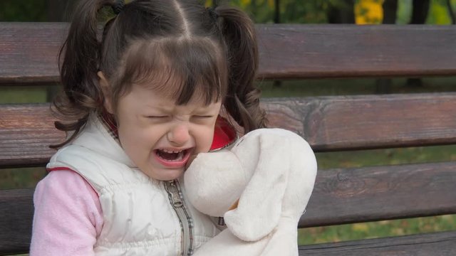 Emotions of the child. Little girl is crying in the park.