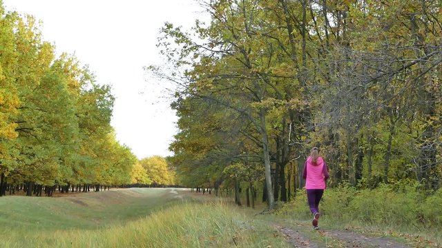 Slow motion Running - woman runner jogging on autumn forest path. Fit female sport fitness model athlete trail running training. Runner gril in sportswear running in park exercising outdoors.