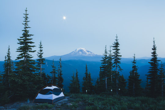 Camping tent in mountains at night with moon rise, Mt, Adams in distance