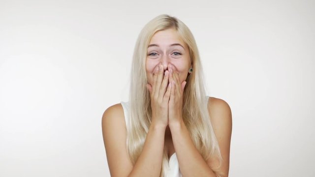 picture of happy woman with long blond hair laughing out loud covering her mouth with hands giggling over white background. Concept of emotions
