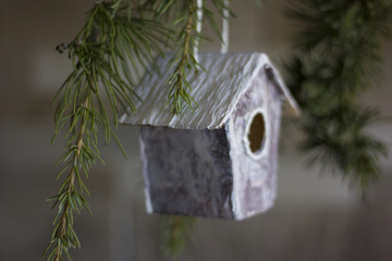 birdhouse hanging on a pine tree branch with pine needles.