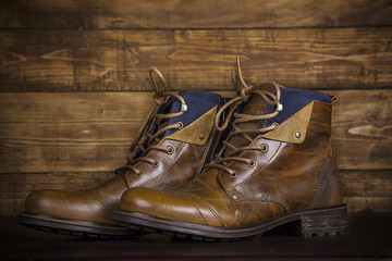 Brown new leather boots vintage background. Worn shoes on the background of an old rustic wooden background. Retro style