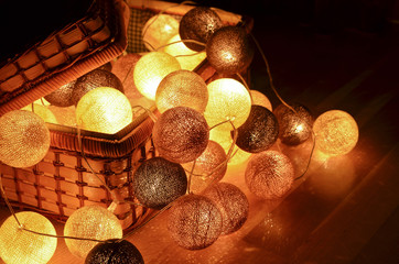 Christmas and New Year cotton light balls string in a basket glowing in the dark. Creative decoration.