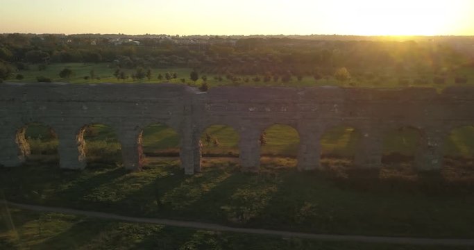 Video from above. Aerial view of the ancient Roman Aqueduct at sunset. Old ruins surrounded by a green public Park (Parco degli Acquedotti) Rome, Italy.