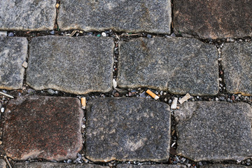 The old historic cobbles and plenty of cigarette butts from cigarettes - texture