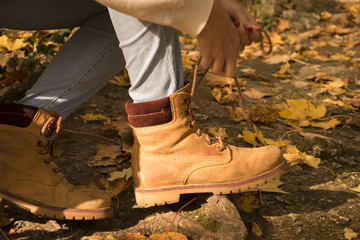 Female tying her laces of her boots camp in autumn