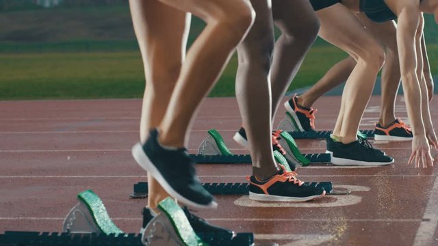  Female runners at athletics track crouching at starting blocks before a race