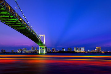 Fototapeta premium Boat traffic at dusk under Rainbow Bridge in Tokyo, Japan