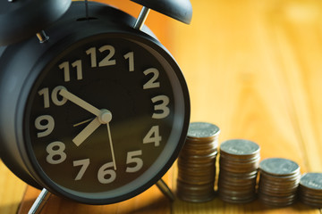Alarm clock and step of coins stacks on working table, time for savings money concept.