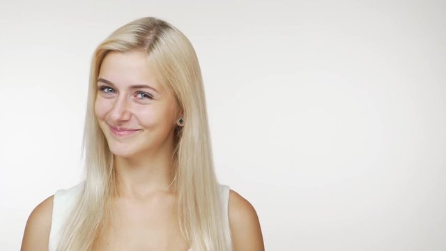 beautiful caucasian female blondie smiling at camera flirting with tricky look over white background copy space. Concept of emotions
