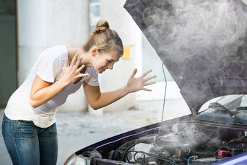 Frustrated Woman Looking At Broken Down Car Engine