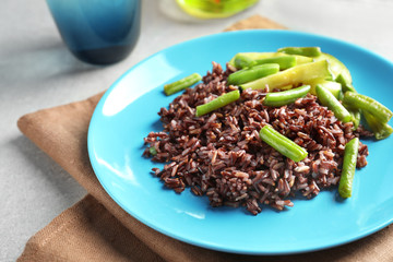 Plate of red rice with vegetables on table, closeup