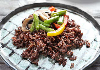 Red rice with vegetables on plate, closeup