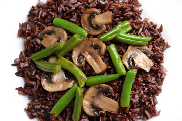 Red rice with mushrooms and green beans on white background, closeup