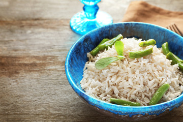 Bowl with brown rice and green beans on wooden table