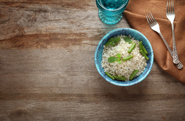 Bowl with brown rice and green beans on wooden table