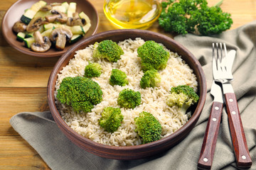 Bowl with brown rice and broccoli on table