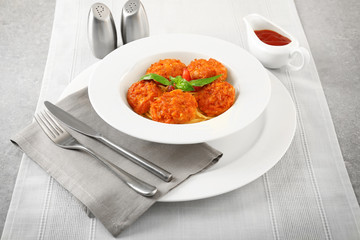 Plate with tasty sausage balls and pasta on table