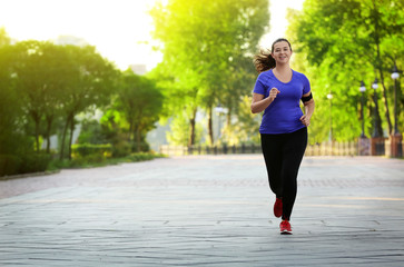 Overweight young woman jogging in park. Weight loss concept