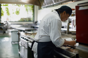 Cook writing the daily shopping list in the kitchen